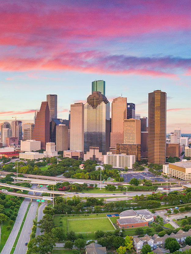 The image shows a city skyline at sunset with the downtown area of Houston prominently visible, featuring the iconic skyscraper known as the Space Needle.