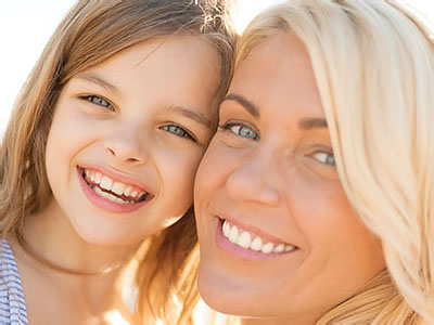 The image depicts a woman and a young girl posing together, with both smiling at the camera.