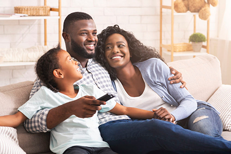 A family of four sitting together on a couch with smiles on their faces.
