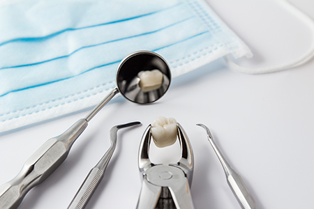 The image shows a collection of dental instruments including a toothbrush with a tooth on top, placed on a blue cloth, arranged against a white background.