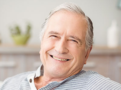 The image shows an elderly man sitting comfortably with his eyes closed, smiling slightly, appearing relaxed and content.
