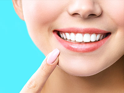 The image shows a close-up of a person smiling with their teeth, using a smartphone with a camera app to take a selfie.